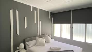 Un dormitorio moderno con cama, mesitas de noche y una ventana con cortinas.