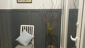 A room with a white chair, a framed botanical illustration on the wall, and a glass door. - Optimus Comfort Fusta 9 (Valencia)