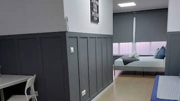 A room with a desk, a chair, a bed with a window, and a wall-mounted sign.
