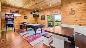 Ein Holzinterieur mit Pooltisch, Spielautomaten und Billardtisch.