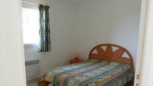 A bedroom with a bed, a nightstand, a lamp, and a window with curtains. - Mini-villa No. 9 - 2/4 people (PORTO VECCHIO)