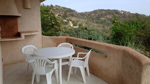A balcony with a round table and four chairs, overlooking a hilly landscape with vegetation. - Mini-villa No. 9 - 2/4 people (PORTO VECCHIO)