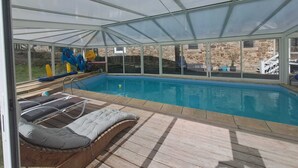 Une piscine couverte avec des chaises longues et un toboggan.