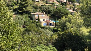 A hillside village with traditional Mediterranean architecture, featuring terraced houses and lush greenery. - Very quietly located 8-person villa with beautiful sea views and private pool. (Le Lavandou)