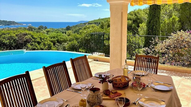 A table set for a meal with a view of a pool and landscape. - Very quietly located 8-person villa with beautiful sea views and private pool. (Le Lavandou)