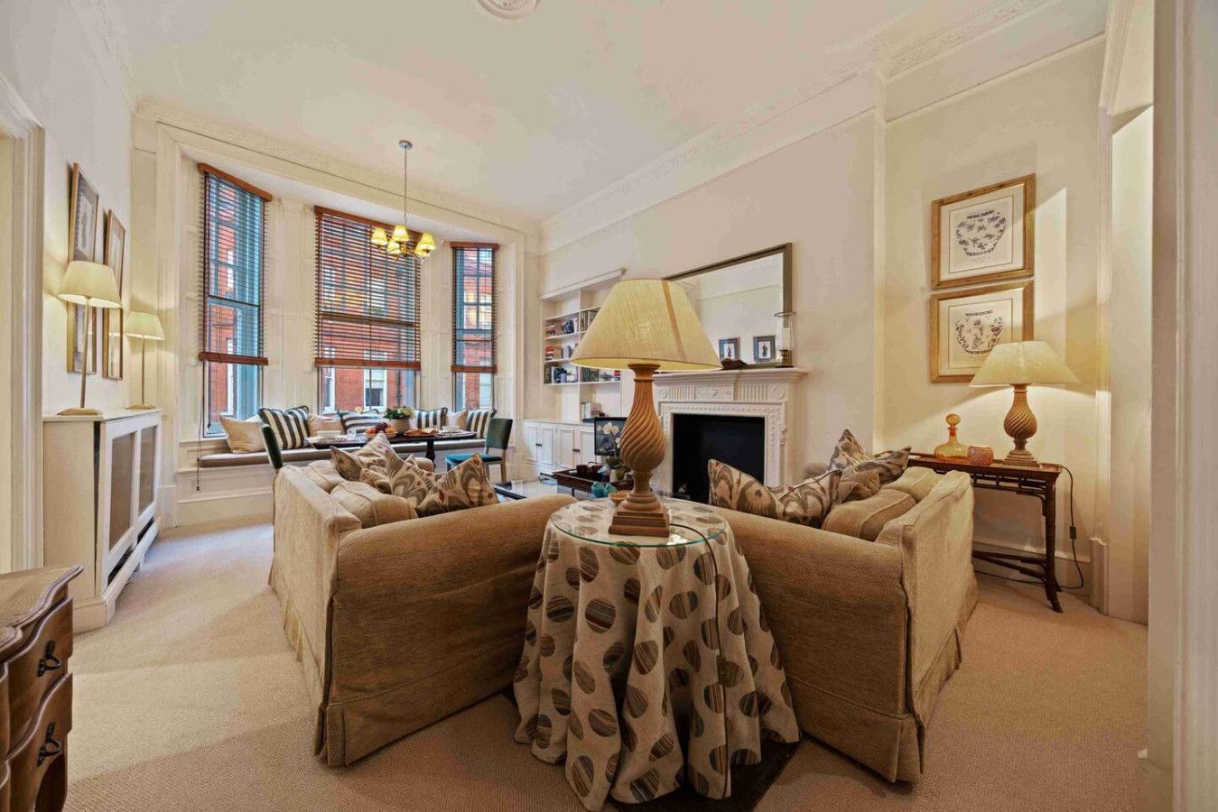 A spacious living room with a fireplace, comfortable seating, and a large window with blinds.