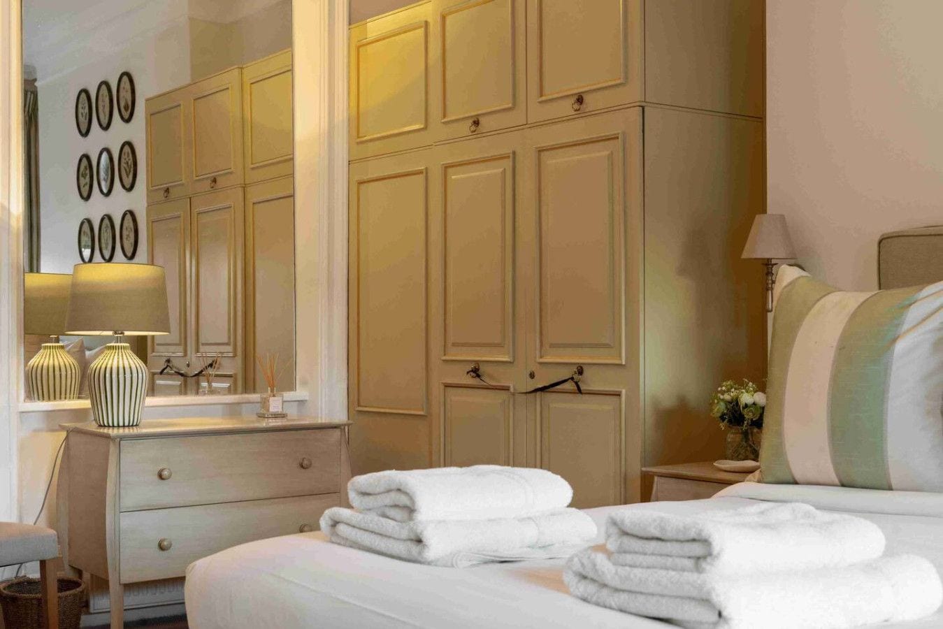 A hotel room with a bed, a dresser, a mirror, and a wardrobe.