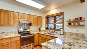 A kitchen with wooden cabinets, granite countertops, stainless steel appliances, and a window with blinds. - Near Trails! Sun-Drenched Durango Escape w/ View (Durango)