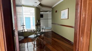 Um quarto espaçoso com piso de madeira, área de jantar com mesa e cadeiras, cozinha com pia e bancada, e um quadro na parede.