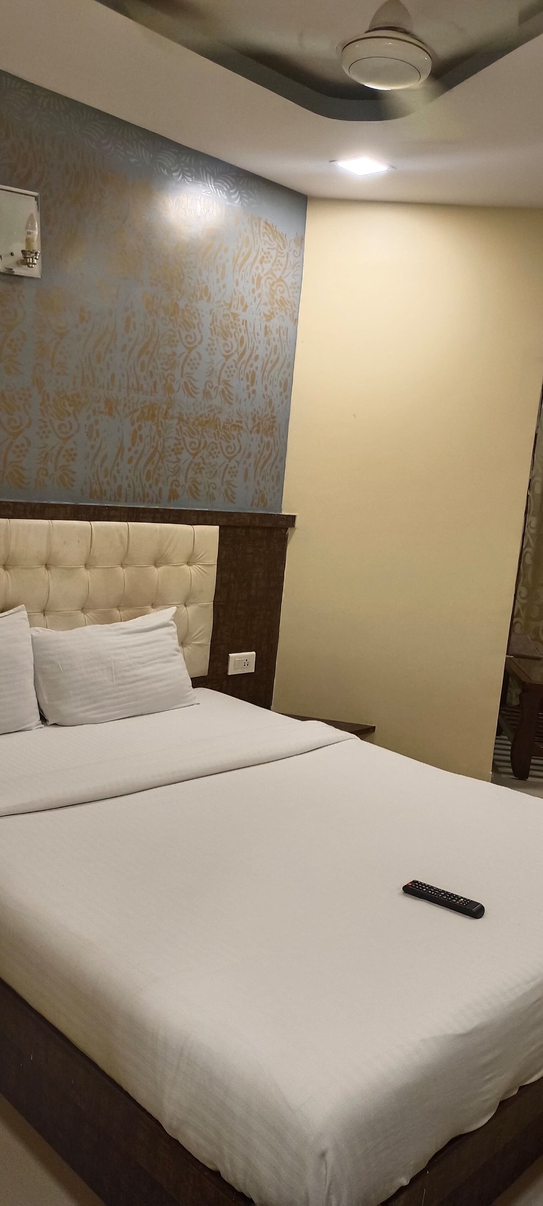 A neatly made bed with white linens and a remote control on it.