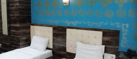 Una habitación de hotel con dos camas, una pared azul con diseño y un muro decorativo de madera.