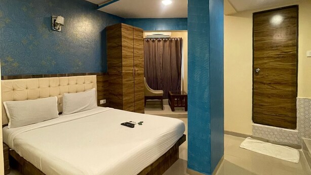 A modern bedroom with a large bed, a wardrobe, and a bathroom. - Hotel Western Court  (Mumbai)
