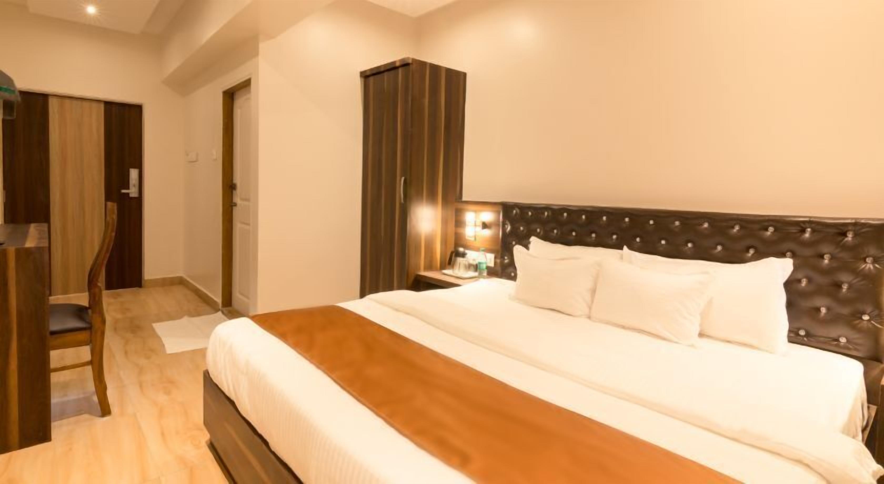 Una habitación de hotel con una cama grande, una silla de madera, un escritorio y un armario.