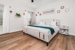 Un dormitorio con cama, mesita de noche y ventana con cortinas.
