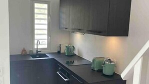 A compact kitchen with dark cabinetry, a sink, and a window with blinds.