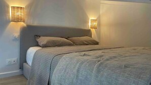 A bedroom with a bed, two wall-mounted lamps, and a sloped ceiling.