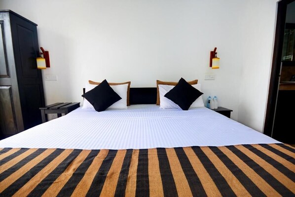 A hotel room with a large bed, two bedside tables, a wardrobe, and wall-mounted lights.