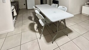 A compact kitchen with a white table and chairs, a refrigerator, and a microwave. - Confortable departamento en Mendoza (Mendoza)