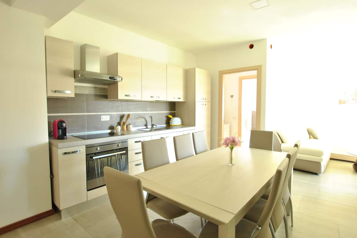 Una cocina moderna con zona de comedor, que incluye armarios, una estufa y una mesa con sillas.