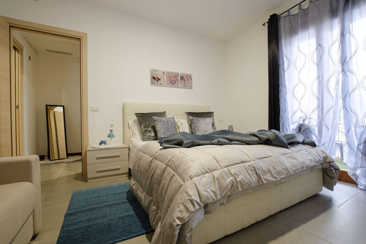 Un dormitorio con cama, mesita de noche y una silla.