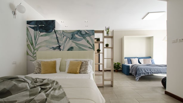 Un dormitorio moderno con una cama grande, una cama más pequeña, una escalera y un estante con plantas.