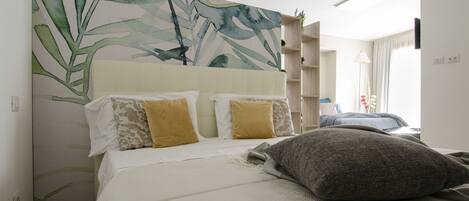 Een hotelkamer met een groot bed, een hoofdbord met een bladmotief en een wandplank.