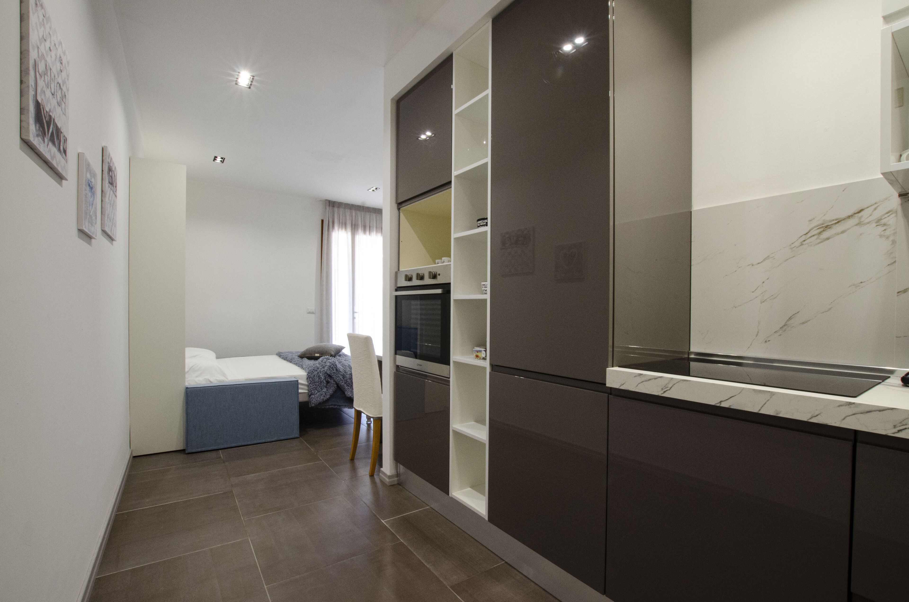 A modern kitchen with dark cabinetry, a marble countertop, and a built-in oven.