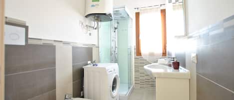 A modern bathroom with a washing machine, bidet, and a shower enclosure.