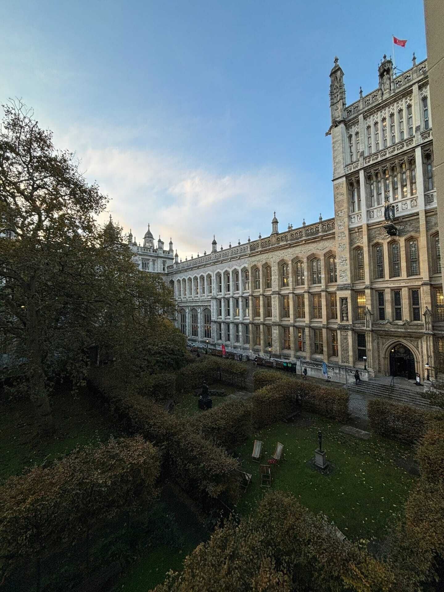 A large, historic building with a symmetrical facade, multiple windows, and a flag on top.