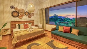 A bedroom with a large bed, a green sofa, and a view of the outdoors. - Few Steps to Beach Private Pool and Jacuzzi (Sardinal)