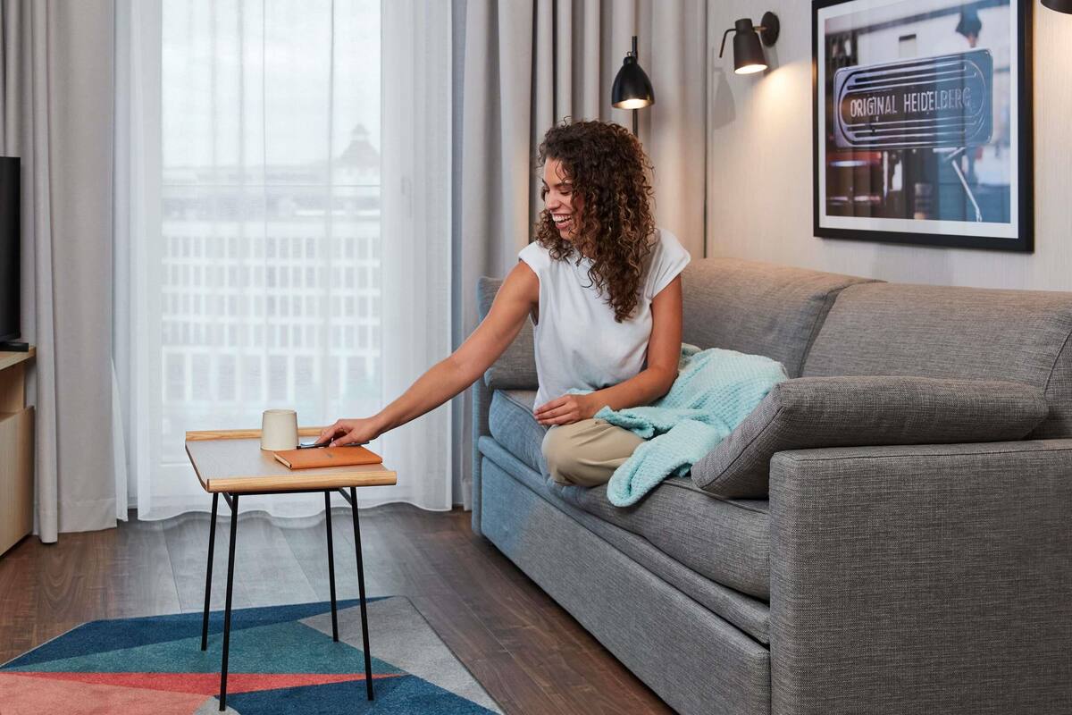 Un salon moderne avec un canapé gris, une petite table en bois et un tapis coloré.