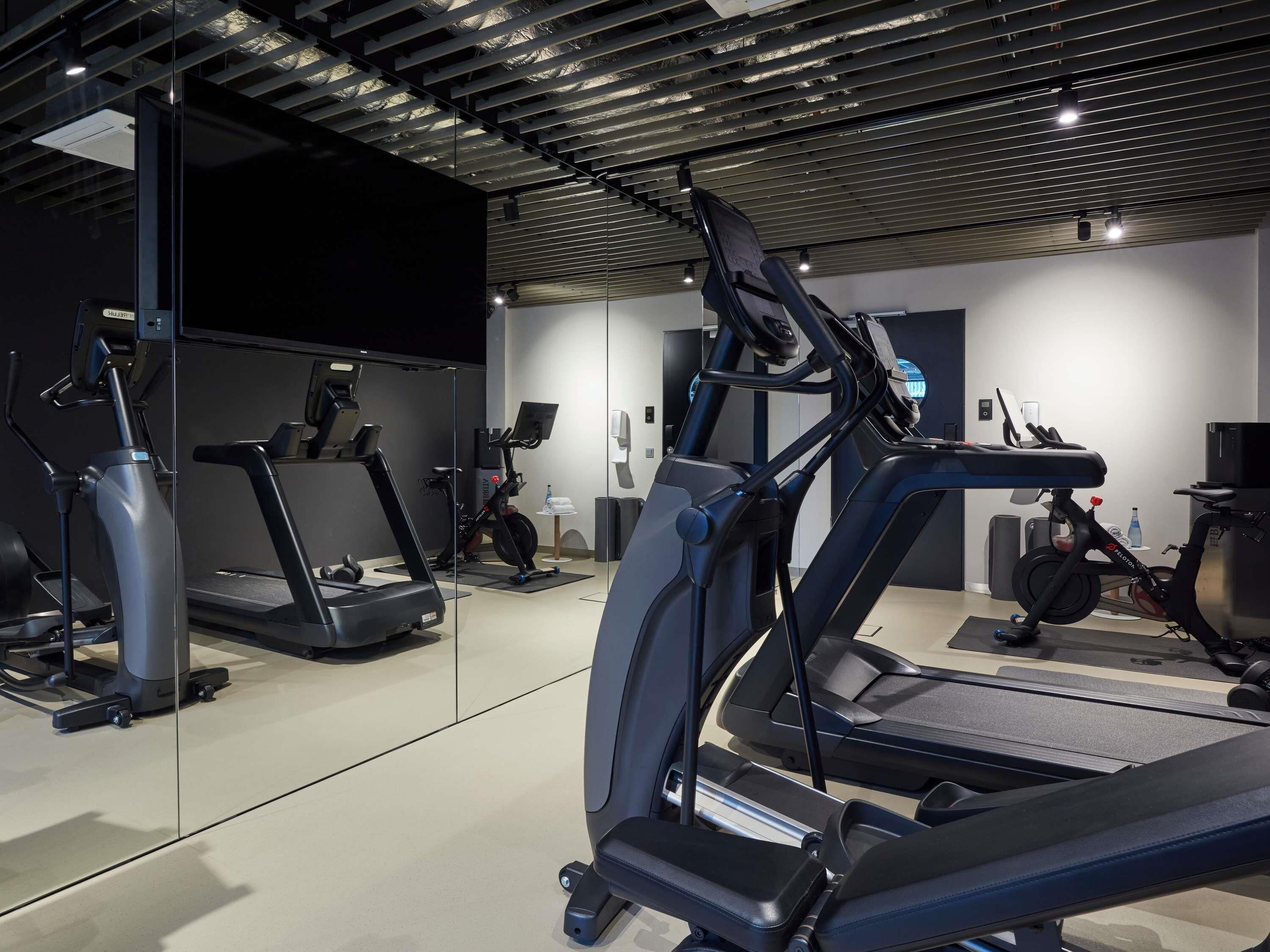 Ett modernt gym med flera löpband, motionscyklar och en vägg med speglar.