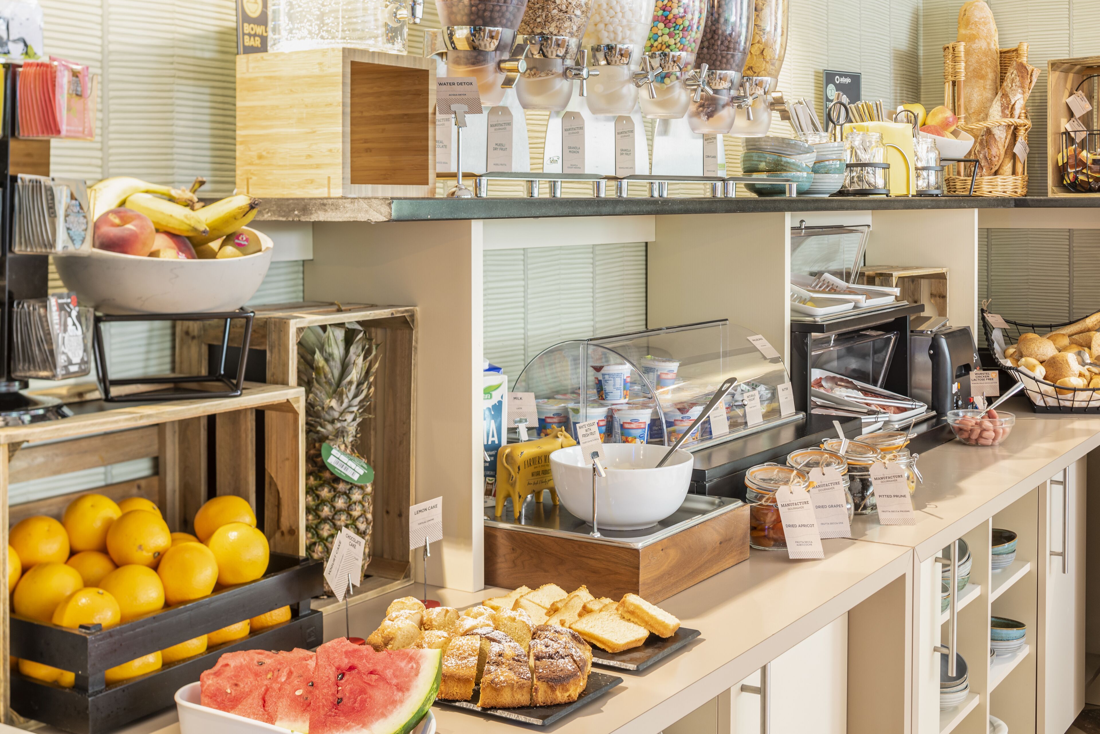 Ein Buffet mit verschiedenen Speisen und Getränken, darunter Obst, Brot und Soßen.
