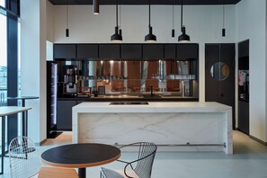 A modern kitchen with a marble island, black pendant lights, and a view of the city through large windows. - Aparthotel Adagio Heidelberg (Heidelberg)