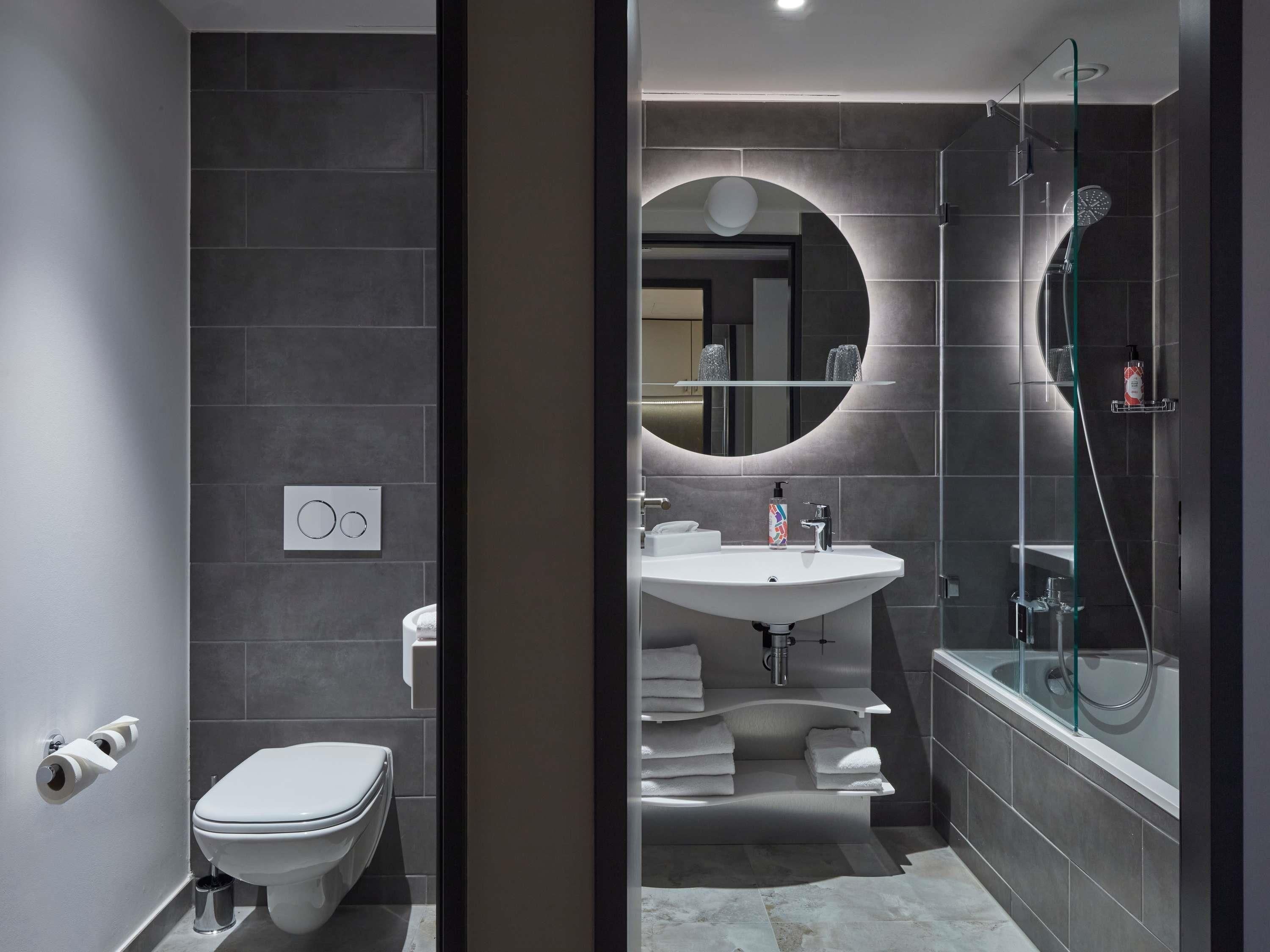 Een moderne badkamer met toilet, wastafel en douche.