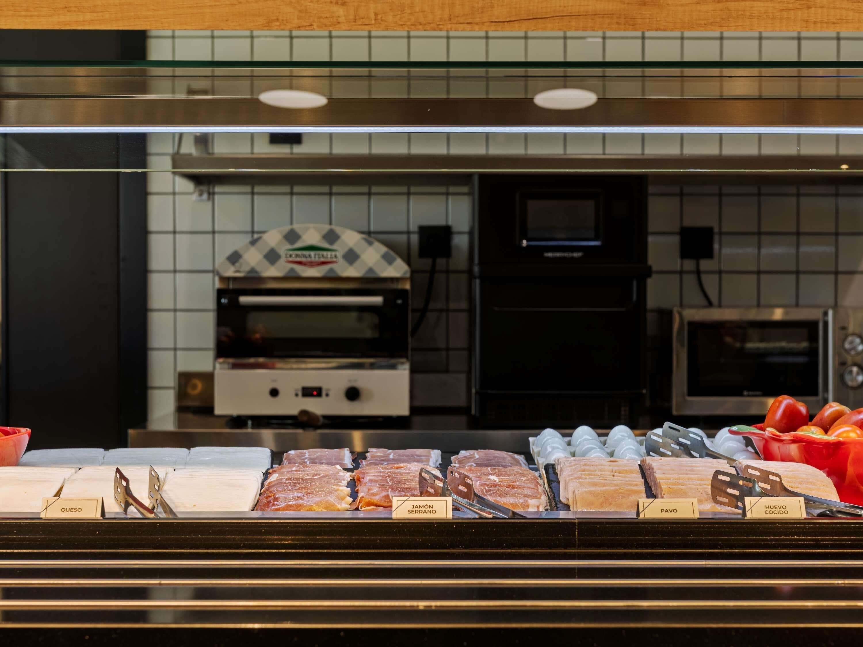 Eine Feinkosttheke mit verschiedenen Fleisch- und Käsesorten, beschriftet auf Spanisch.
