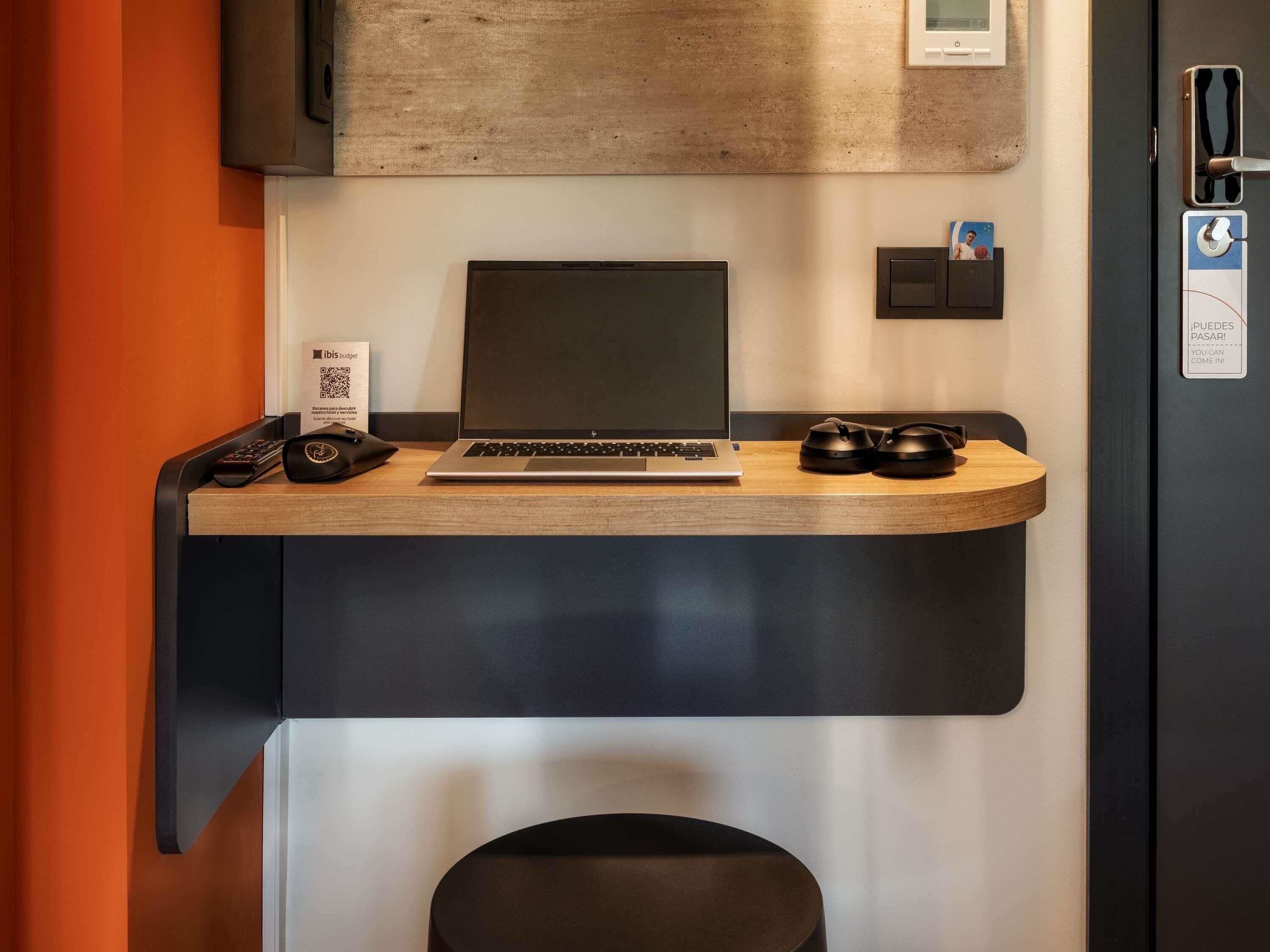 Un mostrador de recepción con una computadora portátil, un teléfono y un par de auriculares.