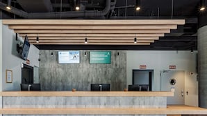 A reception desk with a wooden counter, two monitors, and a sign indicating 'SIN SALIDA' (No Exit).