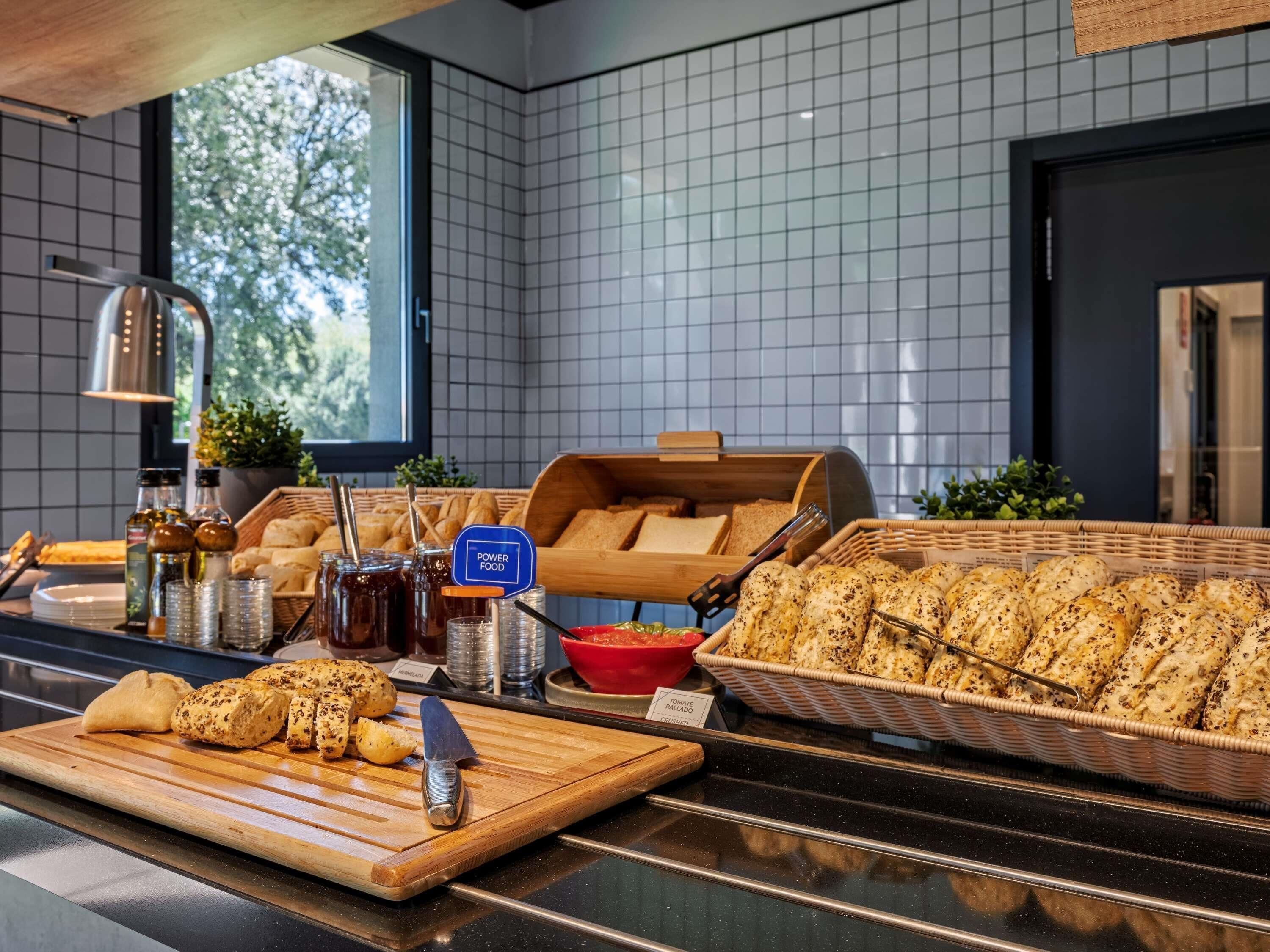 A breakfast buffet with bread, pastries, and condiments.