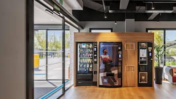 Un interior moderno con una máquina expendedora, una barra de madera y una puerta de cristal que da al exterior.