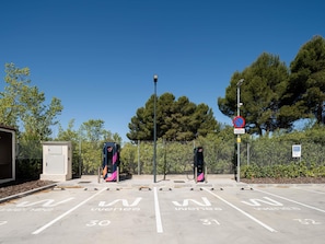 A parking area with electric vehicle charging stations, marked parking spaces, and a no parking sign.