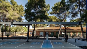 Un estacionamiento techado con espacios reservados para personas con movilidad reducida y un edificio al fondo.