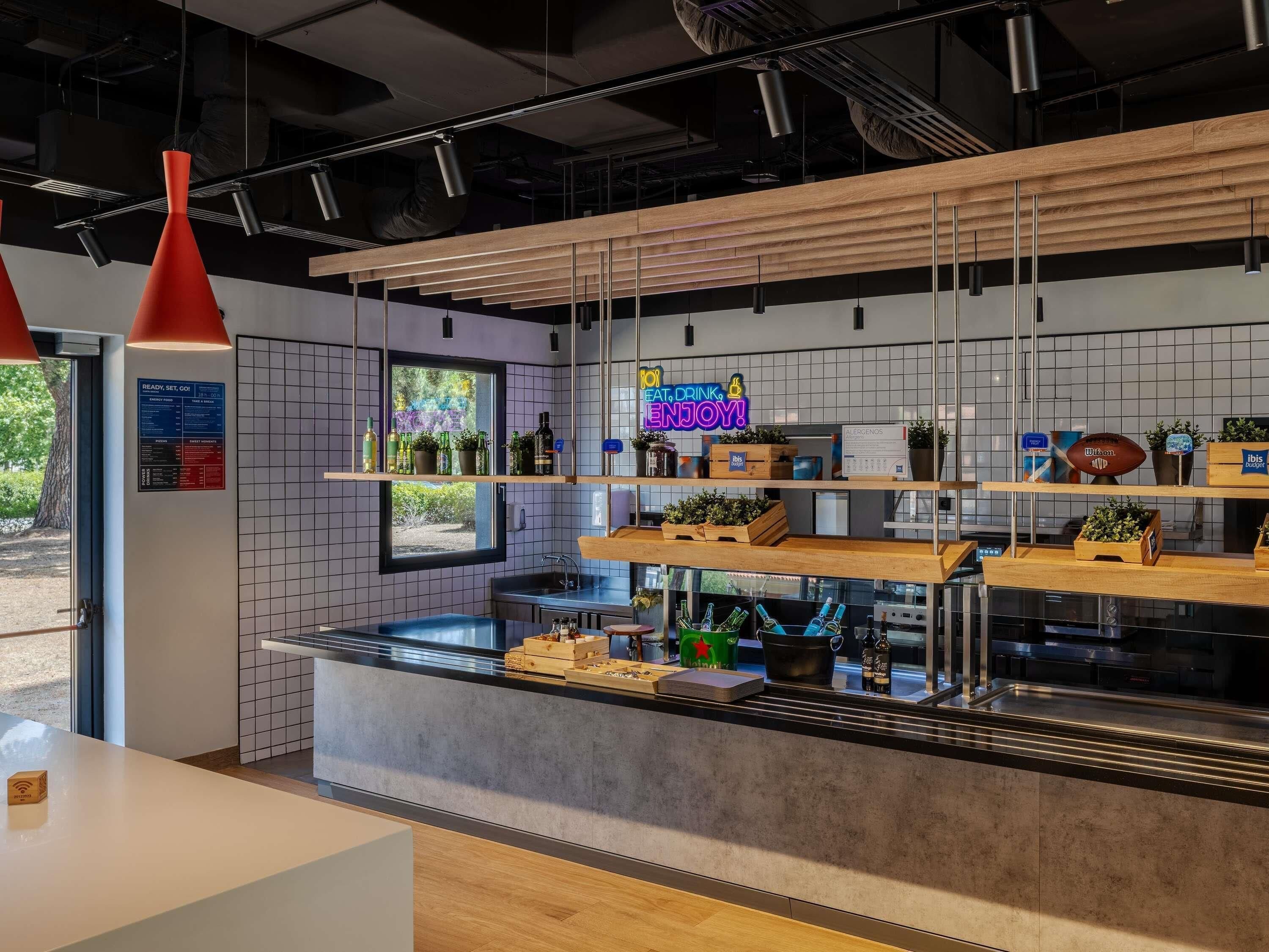 A modern kitchen with wooden shelves, hanging pendant lights, and a neon sign.