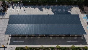An aerial view of a parking lot with marked spaces and a large covered area.
