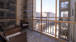 Un balcon agrémenté de meubles en osier, une vue sur le paysage urbain et un immeuble doté de nombreux balcons.