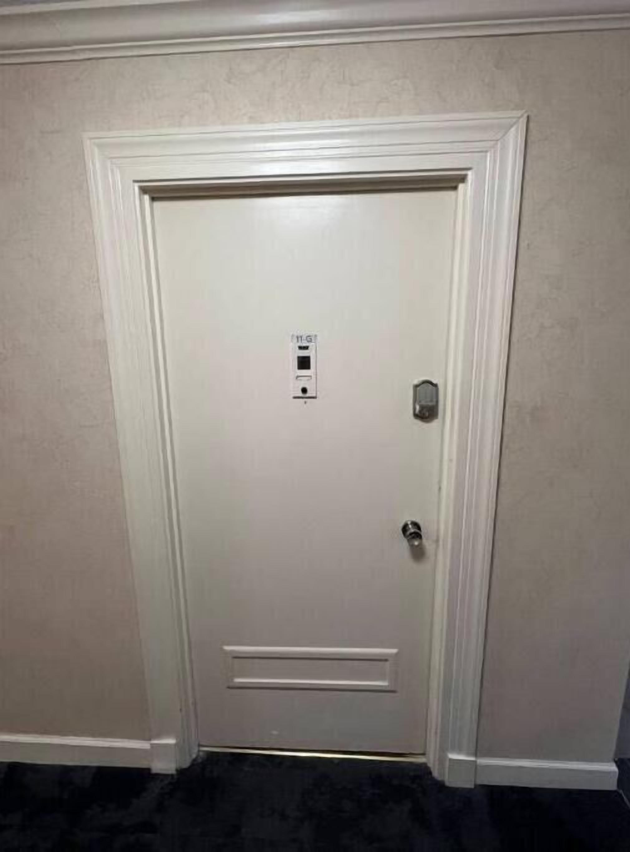 Une porte fermée avec une serrure et un trou de serrure, une petite fenêtre avec une poignée et une prise électrique fixée au mur.