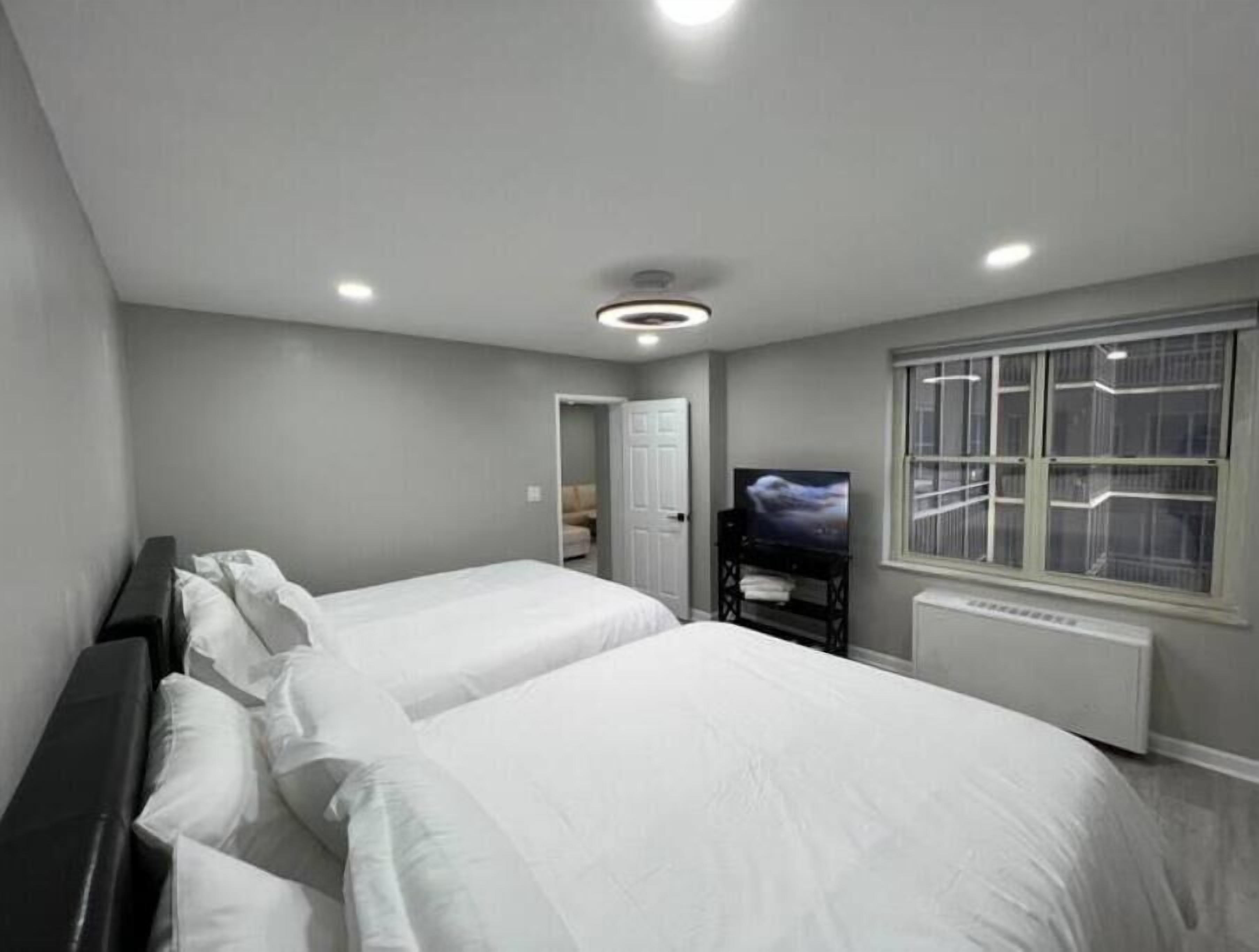 Una habitación de hotel moderna con dos camas, un televisor y una ventana con persianas.