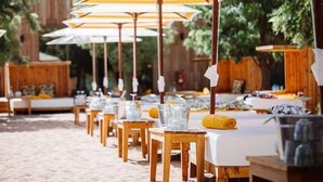 A row of outdoor seating areas with tables and chairs, each under a striped umbrella. - Villa Marrakech Piscine Privée vue sur Golf&atlas (Marrakech)