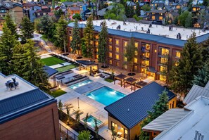 A residential building with a swimming pool, outdoor seating, and a well-maintained lawn.