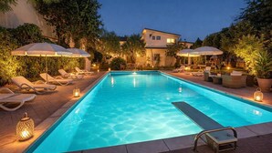 A swimming pool with lounge chairs and umbrellas, surrounded by trees and a building. - Geranium | 2 bedroom, 2 bath, penthouse near the sea (Anastasi III)